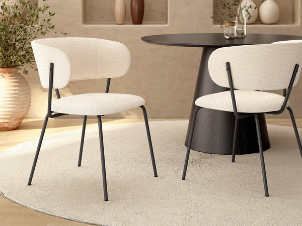 Butaca tapizada en color nácar con patas metálicas negras, asiento y respaldo acolchados, diseño moderno y minimalista.