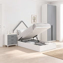 Cama juvenil abatible blanca con cabecero en forma de casita, mesita gris de tres cajones y armario de dos puertas.