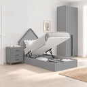Cama juvenil abatible gris de melamina, con cabecero decorativo en forma de casita, mesita de tres cajones y armario de dos puertas.