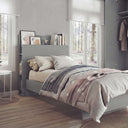 Cama juvenil gris de melamina con cabecero organizador y estantes, vestida con ropa de cama a rayas.