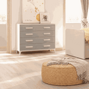 Cómoda dormitorio de cuatro cajones en tonos gris y blanco, con tiradores ovalados claros y patas cortas.