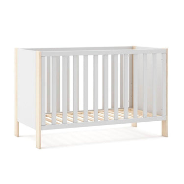 Cuna infantil blanca con laterales de barrotes y estructura de madera clara; diseño sencillo de tablas continuas.