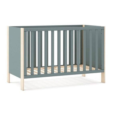 Cuna infantil en tono verde kaki con estructura lacada y detalles de madera clara, barrotes verticales y somier de láminas.
