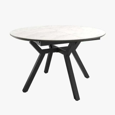 Mesa comedor redonda extensible con acabado efecto piedra y patas metálicas negras.