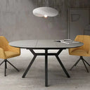 Mesa comedor redonda extensible con acabado efecto piedra y patas metálicas negras.