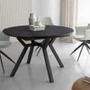 Mesa comedor redonda extensible con acabado efecto piedra y patas metálicas negras.