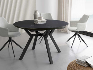 Mesa comedor redonda extensible con acabado efecto piedra y patas metálicas negras.