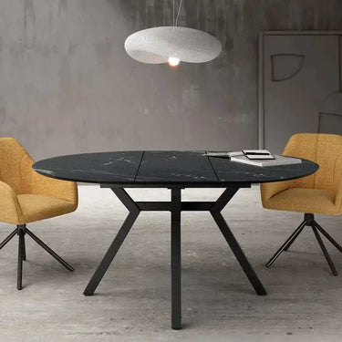 Mesa comedor redonda extensible GIOVANNA con acabado efecto piedra y patas metálicas negras.