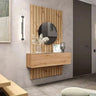 Recibidor de madera color roble claro con panel de listones verticales, espejo redondo y módulo flotante con frente liso.