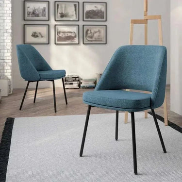 Silla de comedor azul con asiento y respaldo tapizados en tela texturizada, patas metálicas negras y respaldo envolvente.