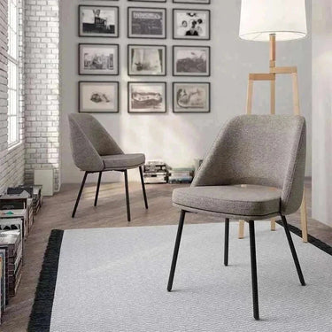 Silla de comedor tapizada en gris texturizado, con asiento y respaldo acolchados y patas metálicas negras.