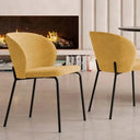 Silla de comedor tapizada en mostaza con respaldo curvo envolvente y patas finas de hierro negro.