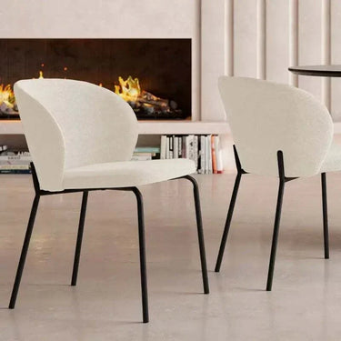 Silla de comedor con tapizado blanco texturizado y respaldo curvo envolvente, sobre patas metálicas negras delgadas.