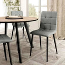 Silla de comedor gris claro tapizada en cuadrantes capitoné, con asiento acolchado y patas metálicas negras.