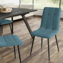 Silla de comedor azul turquesa con tapizado de tejido capitoné en cuadrantes y patas metálicas negras delgadas.