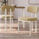 Silla de comedor tapizada color mostaza con patas blancas de metal, asiento y respaldo acolchados, diseño moderno y compacto.