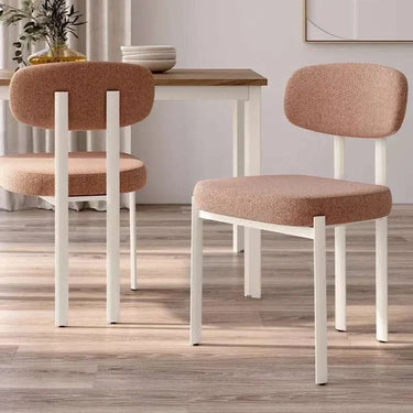 Silla de comedor tapizada en color salmón con patas blancas de metal, respaldo y asiento acolchados, diseño moderno.
