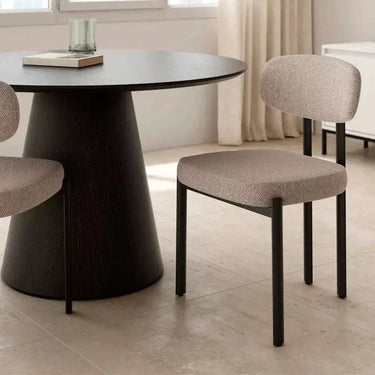 Silla de comedor tapizada en tono beige jaspeado, con asiento y respaldo acolchados y patas rectas de metal negro.