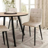 Silla de comedor en beige, con asiento y respaldo acolchados en cuadrantes y patas metálicas negras.