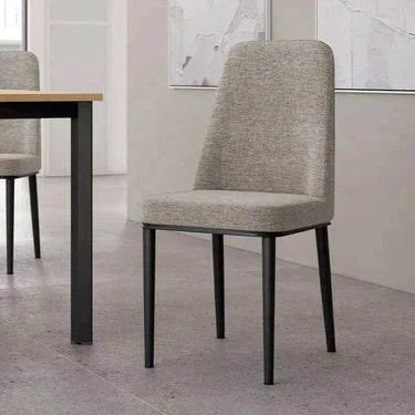 Silla de comedor tapizada en tejido gris jaspeado, con respaldo alto y patas metálicas negras delgadas.