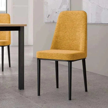 Silla de comedor mostaza tapizada en tejido texturizado, con respaldo alto y patas metálicas negras.