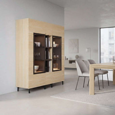 Vitrina de comedor en melamina efecto madera clara, con dos puertas acristaladas, estantes y detalles oscuros.