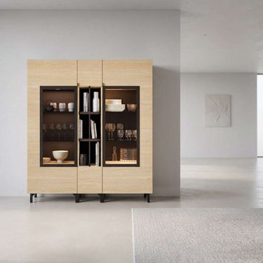 Vitrina de comedor en madera clara melamínica, con dos puertas acristaladas y estantería central estrecha.