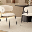 Butaca tapizada en color nácar con patas metálicas negras, asiento y respaldo acolchados, diseño moderno y minimalista.