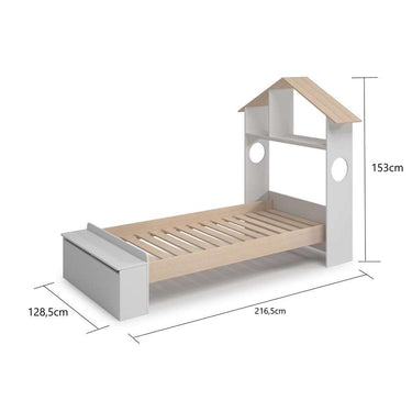 Cama infantil tipo casita en blanco y madera natural, con techo a dos aguas, somier de láminas y arcón integrado.
