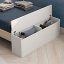 Cama infantil blanca con arcón de almacenaje integrado, tapa abatible con bisagras metálicas y acabado liso laminado.