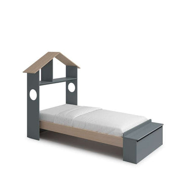 Cama infantil gris con detalles de madera natural, cabecero en forma de casa con estante y arcón al pie.