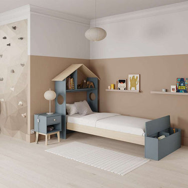 Cama infantil azul grisácea y blanca, con cabecero en forma de casita, estantería y arcón integrados.