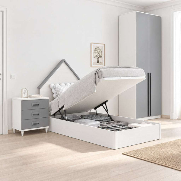 Cama juvenil abatible blanca con cabecero en forma de casita, mesita gris de tres cajones y armario de dos puertas.