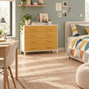 Cómoda dormitorio de cuatro cajones mostaza con estructura blanca, acabado liso y tiradores integrados alargados.