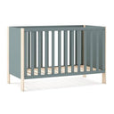 Cuna infantil en tono verde kaki con estructura lacada y detalles de madera clara, barrotes verticales y somier de láminas.