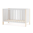 Cuna infantil blanca con estructura de madera, barrotes verticales y patas en acabado de madera natural.