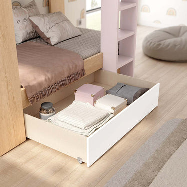 Litera juvenil de madera en tonos naturales y rosa pálido, con cama inferior extraíble y cajón blanco con ruedas para almacenaje.
