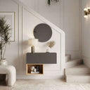Recibidor suspendido de melamina gris oscuro y madera clara, con puerta lisa, hueco abierto y espejo redondo.