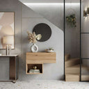 Recibidor de madera clara con módulo colgante de frente liso y cubo abierto inferior; espejo redondo negro.