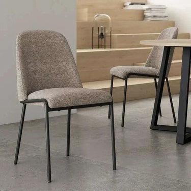 Silla de comedor gris con tapizado texturizado en asiento y respaldo, patas metálicas negras de líneas rectas.