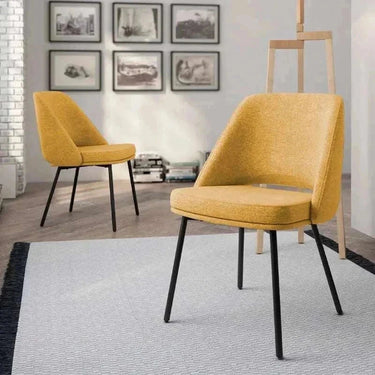 Silla de comedor mostaza tapizada en tela texturizada, con asiento acolchado, respaldo envolvente y patas metálicas negras.