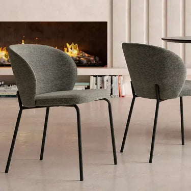 Silla de comedor gris con tapizado texturizado en asiento y respaldo curvo, y patas metálicas negras delgadas.