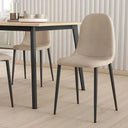 Silla de comedor beige tapizada en tela lisa, con respaldo curvo y patas metálicas negras sin reposabrazos.