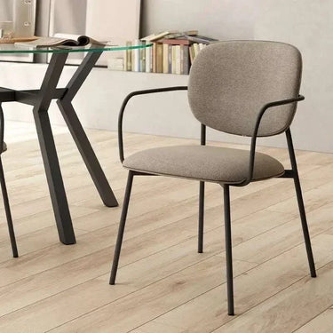 Silla de comedor tapizada gris con reposabrazos y patas metálicas negras, diseño moderno y sencillo.