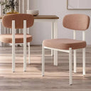 Silla de comedor tapizada en color salmón con patas blancas de metal, respaldo y asiento acolchados, diseño moderno.