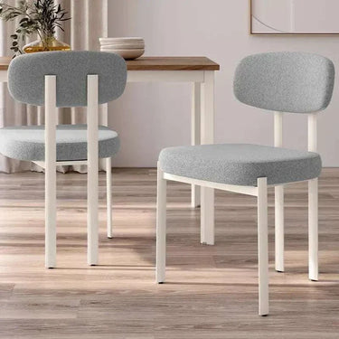 Silla de comedor tapizada en gris con patas blancas de metal, asiento y respaldo acolchados, diseño moderno y sencillo.