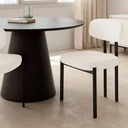 Silla de comedor con asiento y respaldo tapizados en blanco, de textura suave y patas metálicas negras rectas.