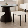 Silla de comedor con asiento y respaldo tapizados en blanco, de textura suave y patas metálicas negras rectas.