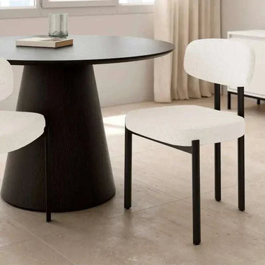 Silla de comedor con asiento y respaldo tapizados en blanco, de textura suave y patas metálicas negras rectas.