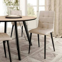 Silla de comedor en beige, con asiento y respaldo acolchados en cuadrantes y patas metálicas negras.